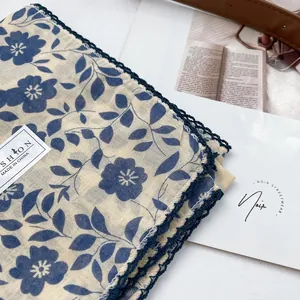 Detail of floral cotton scarf with navy crochet lace edges and brand fashion tags