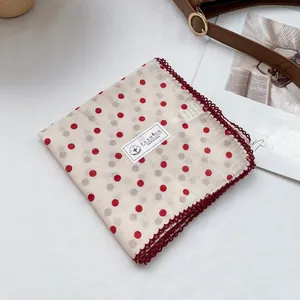 Detail of white cotton bandana with red polka dots and decorative crochet lace trim