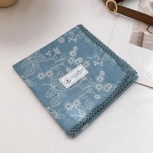 Detail of blue floral cotton scarf featuring delicate lace edges and white daisy patterns