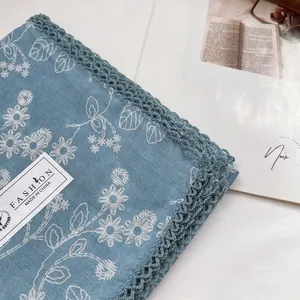 Detail of light blue cotton scarf with white floral print and delicate lace crochet edge