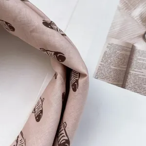 Detail eines hellrosa Baumwoll-Leinen-Schals mit schwarzem Fischprint und feinen Nähten