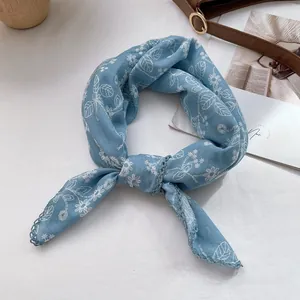 Detail of light blue floral scarf with elegant lace trim and botanical prints