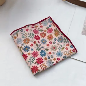 Détails de broderie florale et bords rouge foncé sur un foulard en coton abricot rétro