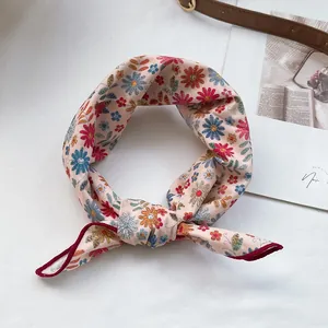 Détail d'un foulard en coton noué avec un motif floral de marguerites multicolores