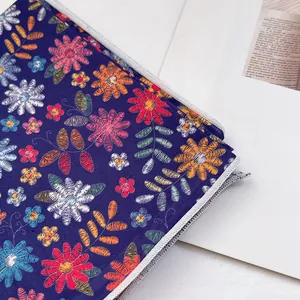Détail de la broderie florale bleu foncé et de la fermeture éclair sur un sac en coton