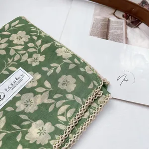 Detail of green floral cotton scarf featuring delicate beige crochet lace edge and label