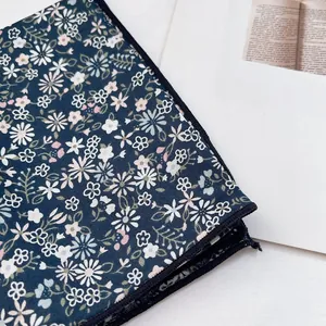 Detailed view of the navy floral silk scarf showing small daisies and stitched edges
