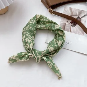 Detailed view of green floral cotton scarf with lace edges tied on a brown leather bag