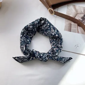 Close-up of a navy floral silk hair ribbon with knot detail on a white background