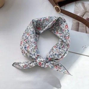 Close-up of floral print chiffon hair ribbon tied on a leather bag with magazine background
