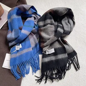 Blue and grey striped wool scarf with fringe and brand label on textured background