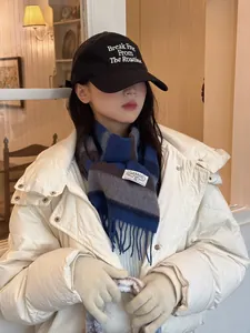 Detail of blue striped wool scarf with white logo tag paired with puffy down jacket