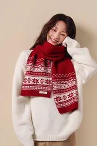 Detail of red knit wool scarf with Fair Isle patterns and 100% Wool quality label