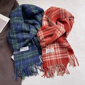 Detail view of plaid 100% pure wool scarves with fringe edges and brand labels