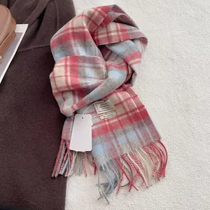 Detail of 100% wool scarf featuring pink and blue plaid pattern with fringe edges