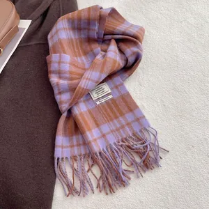Detail of 100% wool scarf featuring a purple and brown plaid pattern and fringe