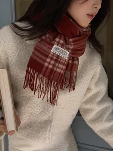 Detail of red and beige wool scarf featuring classic plaid pattern and fringe