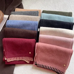 Detailed close-up of wool blend scarves showing various colors and a gold logo charm