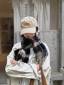 Detail of wool plaid scarf with fringes and embroidered baseball cap for winter wear