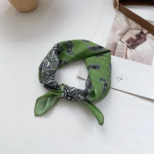 Detail eines grünen Baumwolltuchs mit Paisley-Muster und fein gesäumten Kanten im Fokus