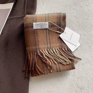 Detail of wool scarf featuring classic brown and blue plaid pattern with handmade tassels