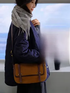 Détail d'un sac messager vintage en velours côtelé marron avec lanières en cuir et boucles
