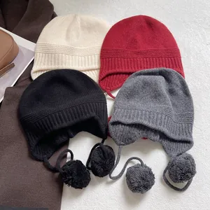 Gorros de lana gruesa con orejeras y pompones en blanco, rojo, negro y gris oscuro