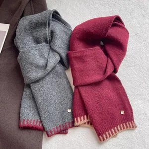 Soft wool blend knitted scarf with contrast stitching in grey and burgundy colors.