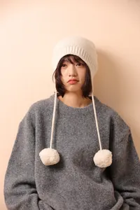 Detalle del gorro de punto blanco roto con pompones suaves y textura gruesa acogedora