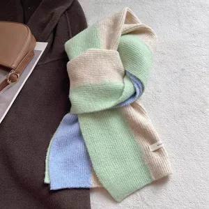 Detail of color-block knit scarf showing soft texture and brand tag on brown wool coat