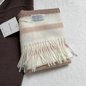 Detail of soft striped wool scarf with fringe and brand label in neutral tones