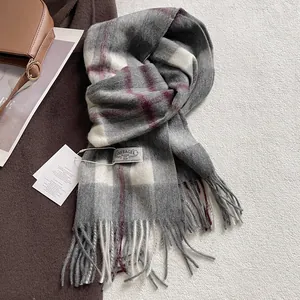 Close-up of wool plaid scarf with fringes and woven brand label in winter style