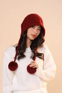 Close-up of dark red wool knit hat with thick texture and soft plush pom-pom detail