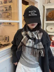 Detalle de bufanda de lana a cuadros marrones estilo británico con flecos y gorra negra