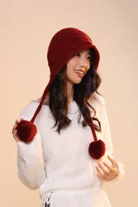 Detail of dark red wool knit earflap hat with dual pom-poms for winter style