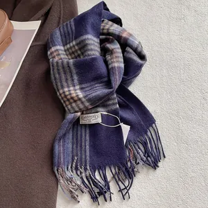 Detail of wool plaid scarf with fringes and brand label on a cozy winter coat