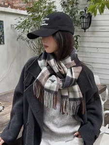 Detalle de bufanda de lana a cuadros marrones estilo británico con flecos y gorra bordada