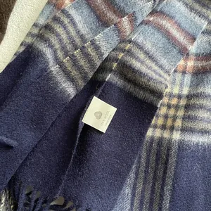 Detail of 100 percent pure wool label and soft fringe on vintage plaid winter scarf