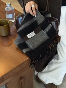 Close-up of a thick wool scarf with black and brown plaid pattern and fringe detail