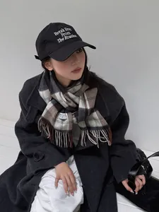 Detalle de bufanda clásica de lana a cuadros con borlas y abrigo gris de moda