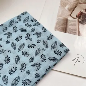 Detailansicht eines hellblauen Baumwollschals mit schwarzem botanischem Blumendruck