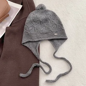 Close-up of gray wool knit hat with pom-pom and diamond texture detail