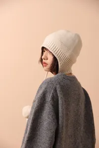 Primer plano detallado de un gorro de lana blanco crema con orejeras y punto acanalado