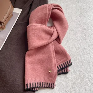 Detail of pink wool blend scarf showing soft knit texture and black striped hem finish