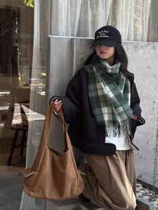 Bufanda de lana a cuadros marrones estilo británico con chaqueta negra y bolso de ante