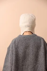 Primer plano detallado de un gorro de lana crema de lana mostrando la etiqueta de 100% lana pura