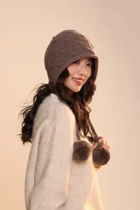 Detailed knit texture of a brown wool earflap hat with decorative side pompoms