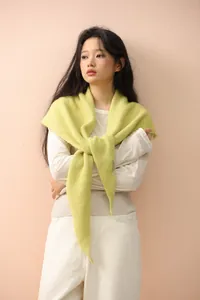 Detailed knit texture of a light green shawl with a minimalist white side label