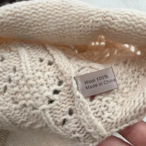 Detail view of the washing label showing 100% wool material on ivory crochet knit hat