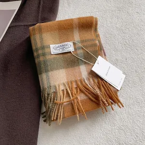 Detailed close-up of wool plaid scarf texture with tassel edges and brand tag